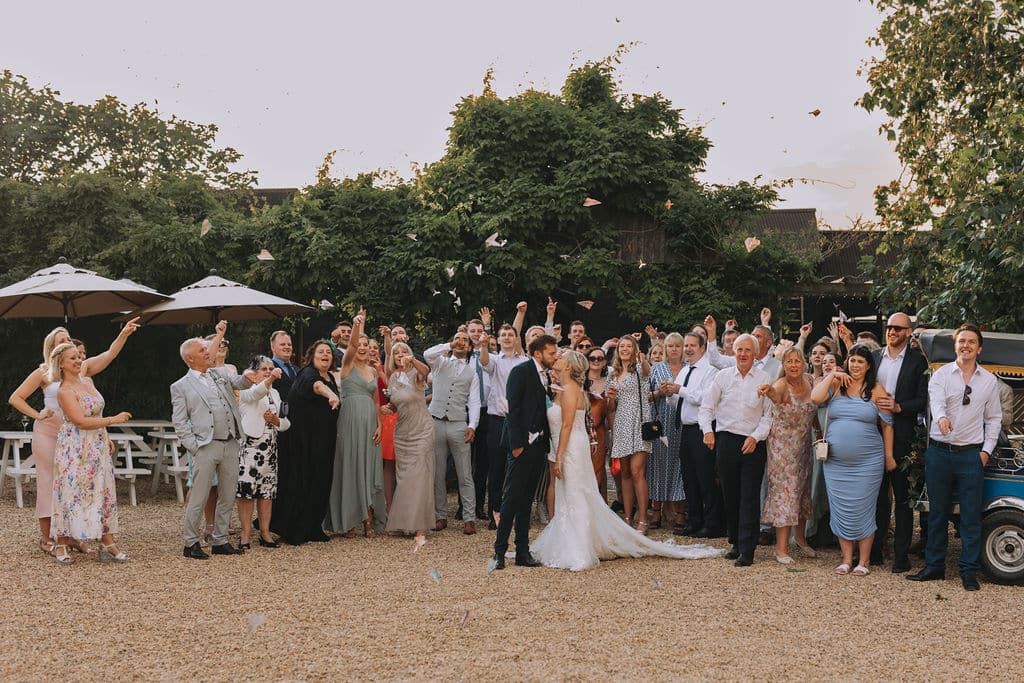 Bride, Groom and their guests doing an airplane throw in the Courtyard at outdoor garden venue