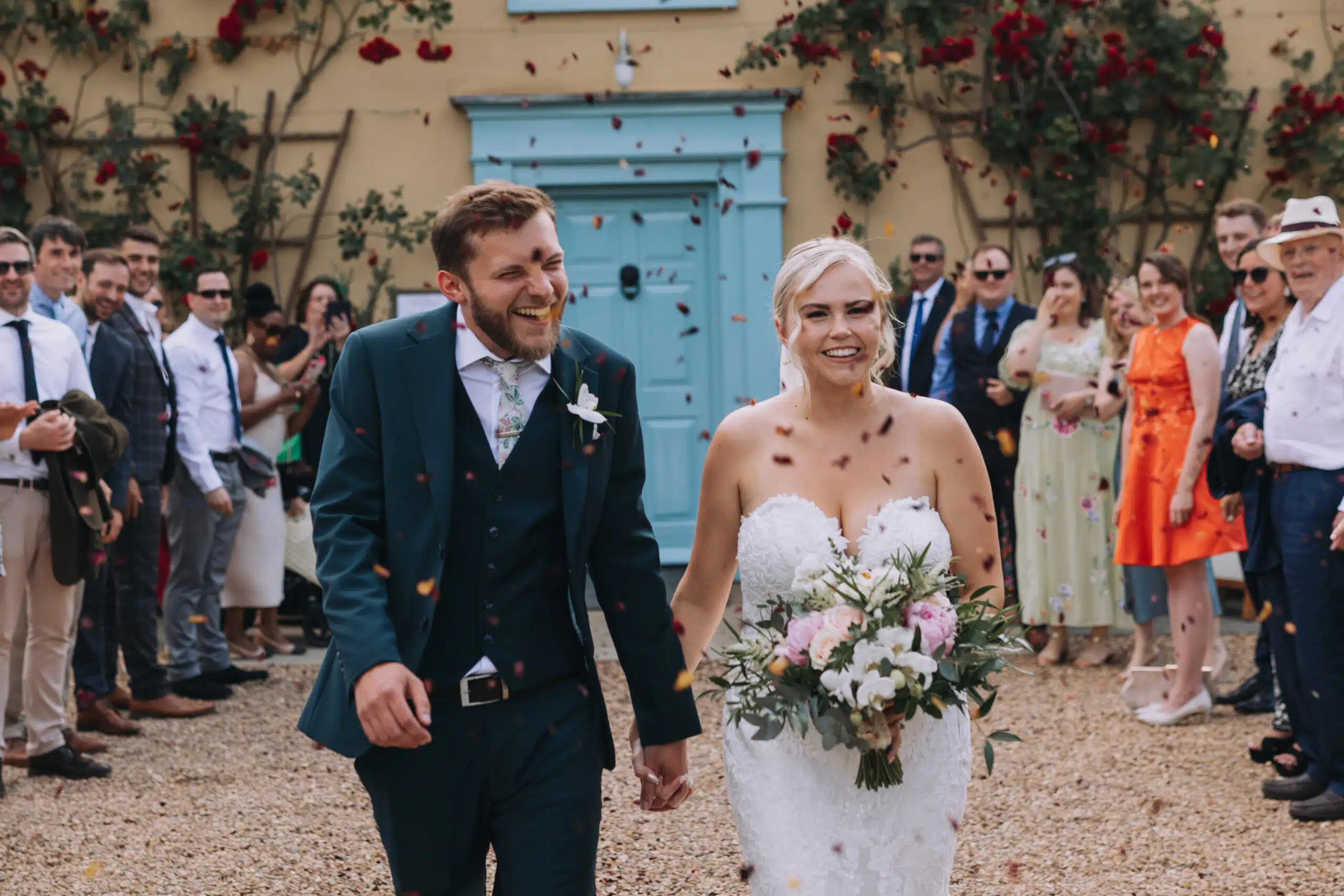 Bride and Groom having beautiful confetti shot front of charming farmhouse at countryside wedding venue