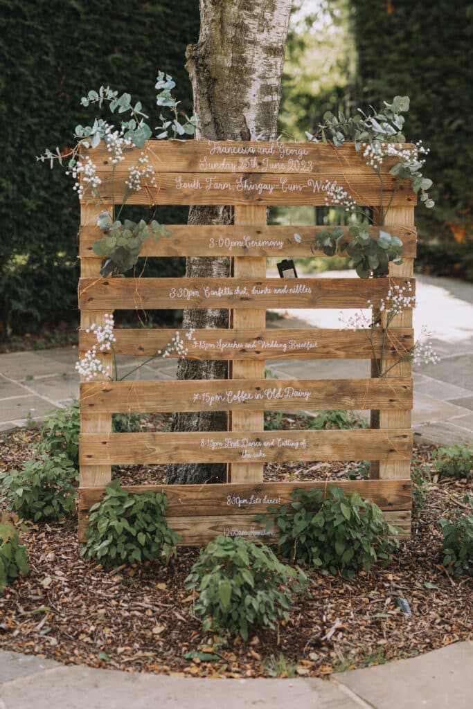 Rustic order of the day presented on a pallet at outdoor garden wedding venue