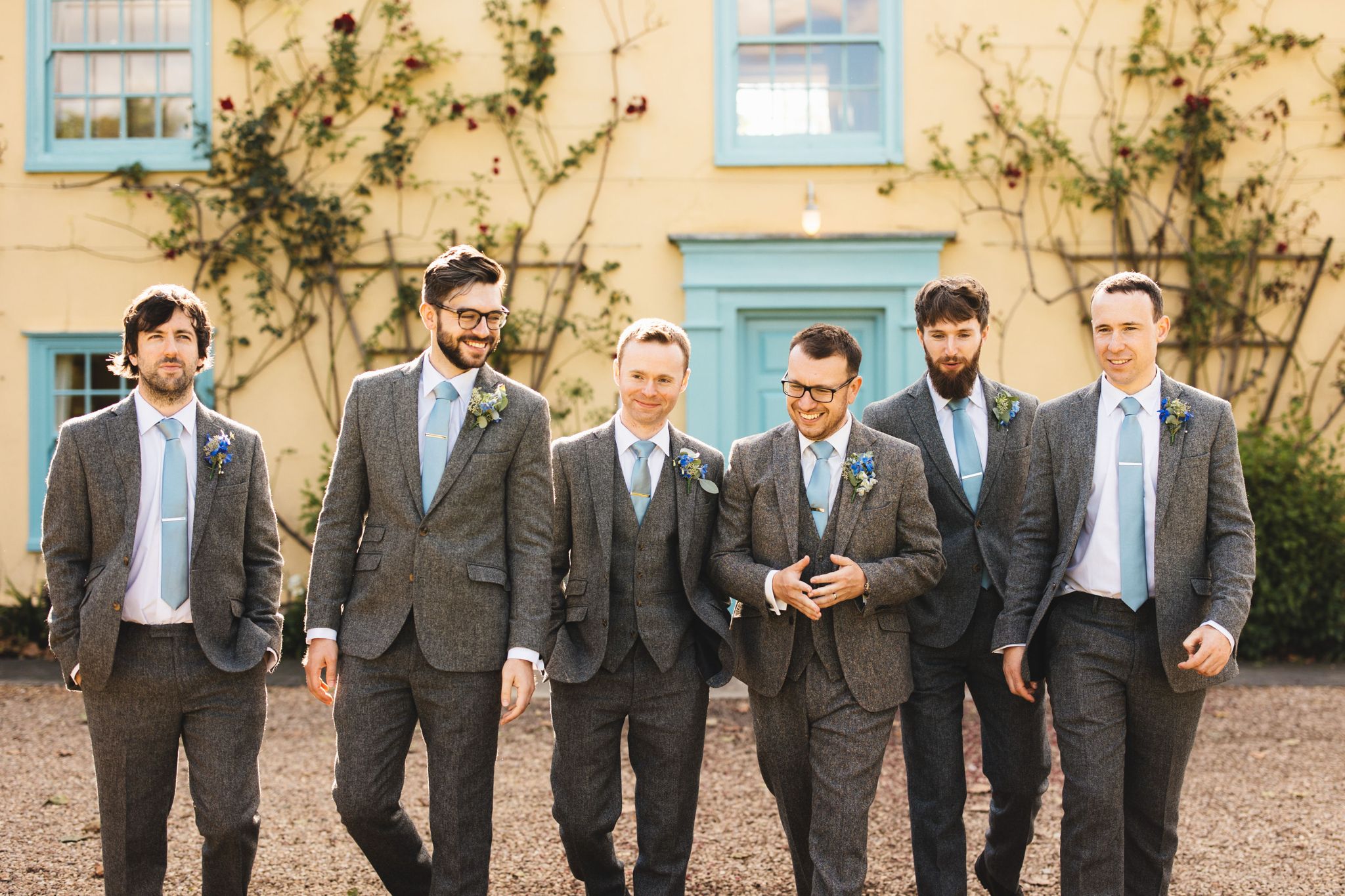 Groom at the front of the Farmhouse with his ushers having a photo before their indoor ceremony at barn wedding venue