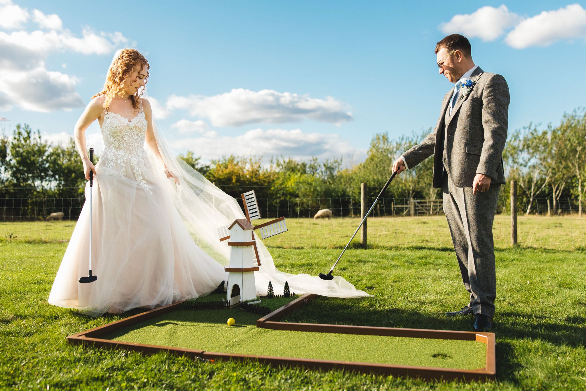 Bride and Groom playing crazy golf in the sheep meadow at outdoor countryside wedding venue