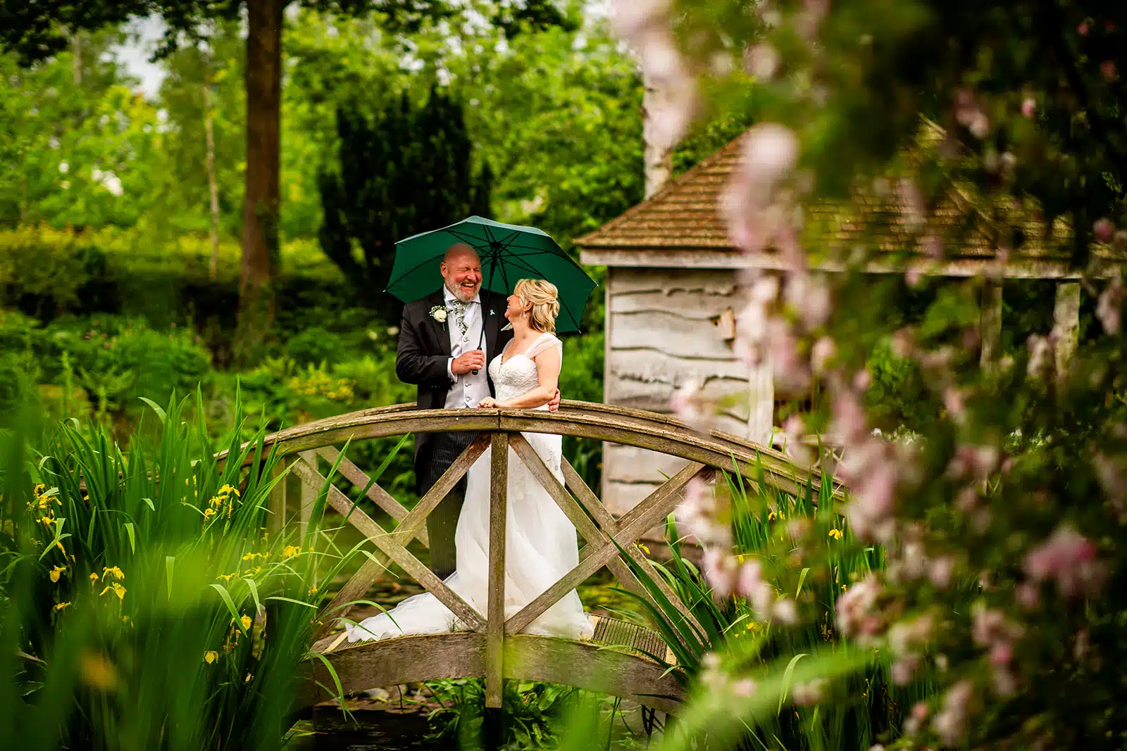 Bride and Groom on the Monet Bridge adorned with blossoms and the Summer House in view