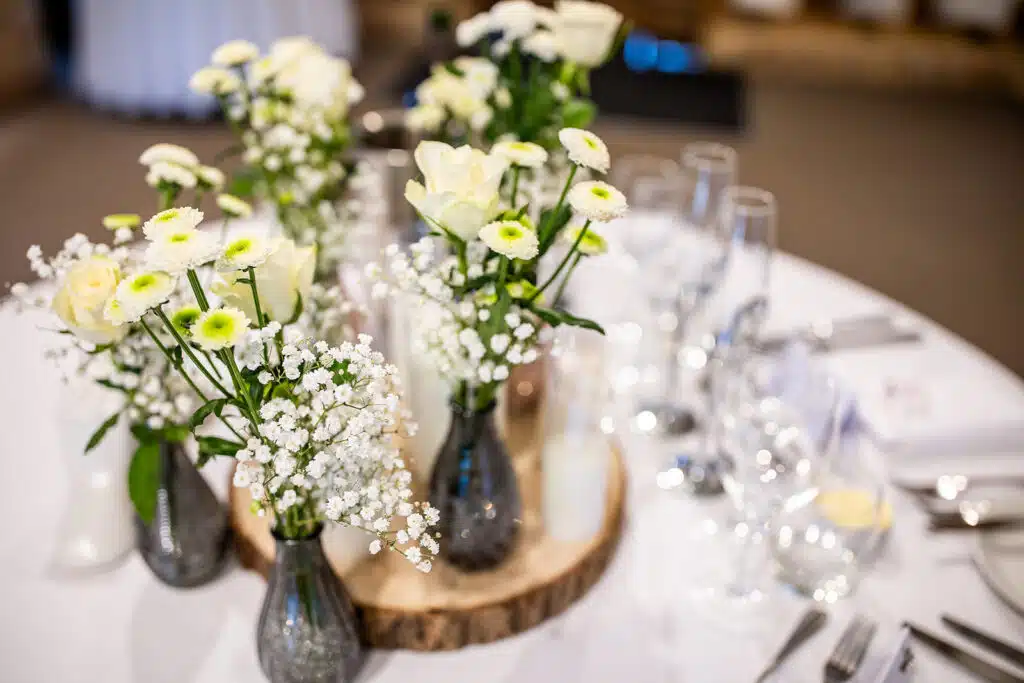 White and green rustic floral display on guests tables in the Tudor Barn