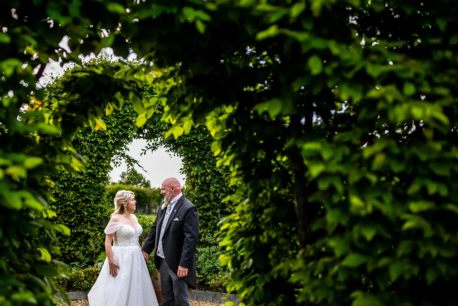 Bride and Groom standing in the center of the green hedgerow in Kitchen Garden where South Farm promote sustainable weddings