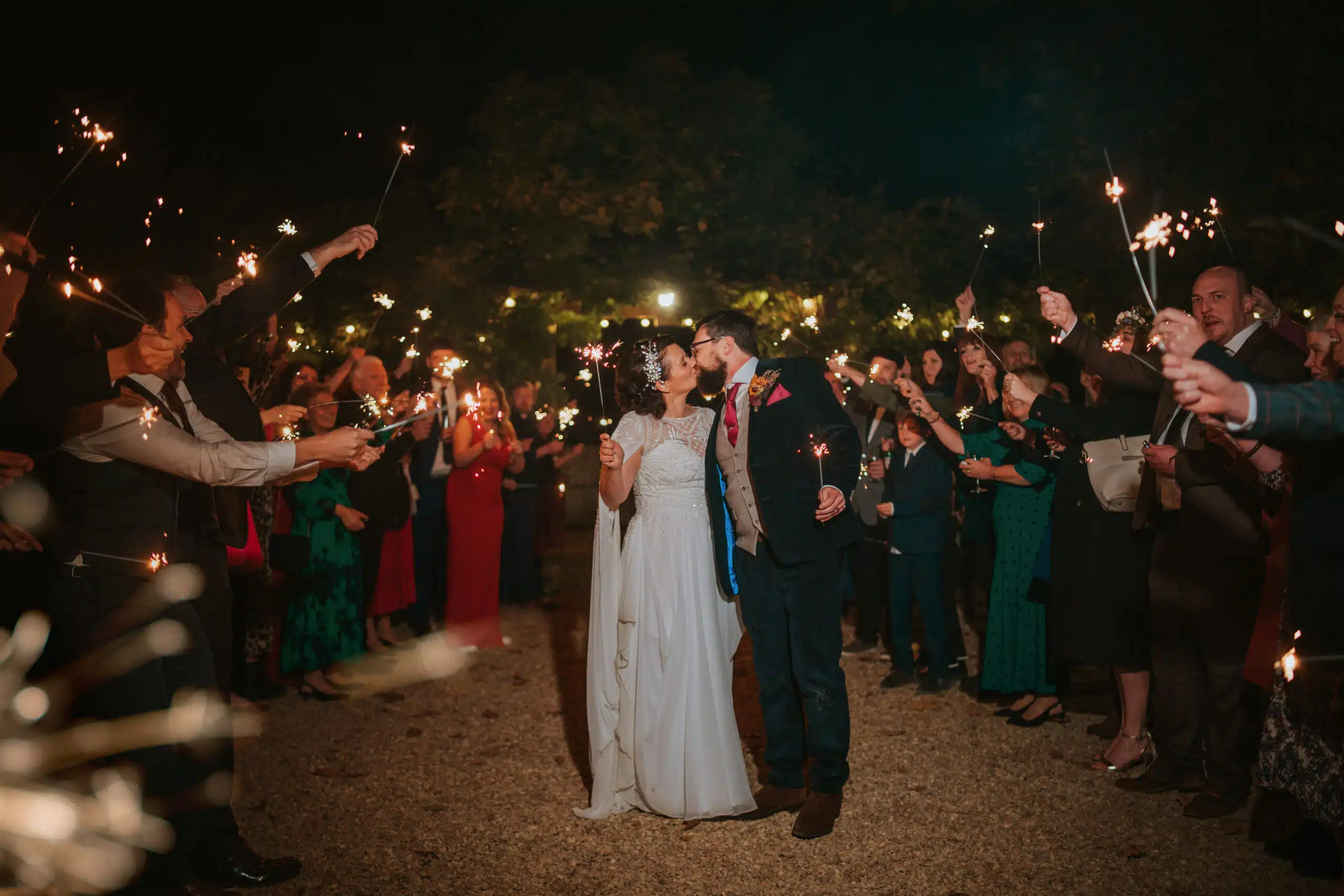 Bride and Groom having a sparkler photo in the evening with their guests in the Courtyard at South Farm wedding venue