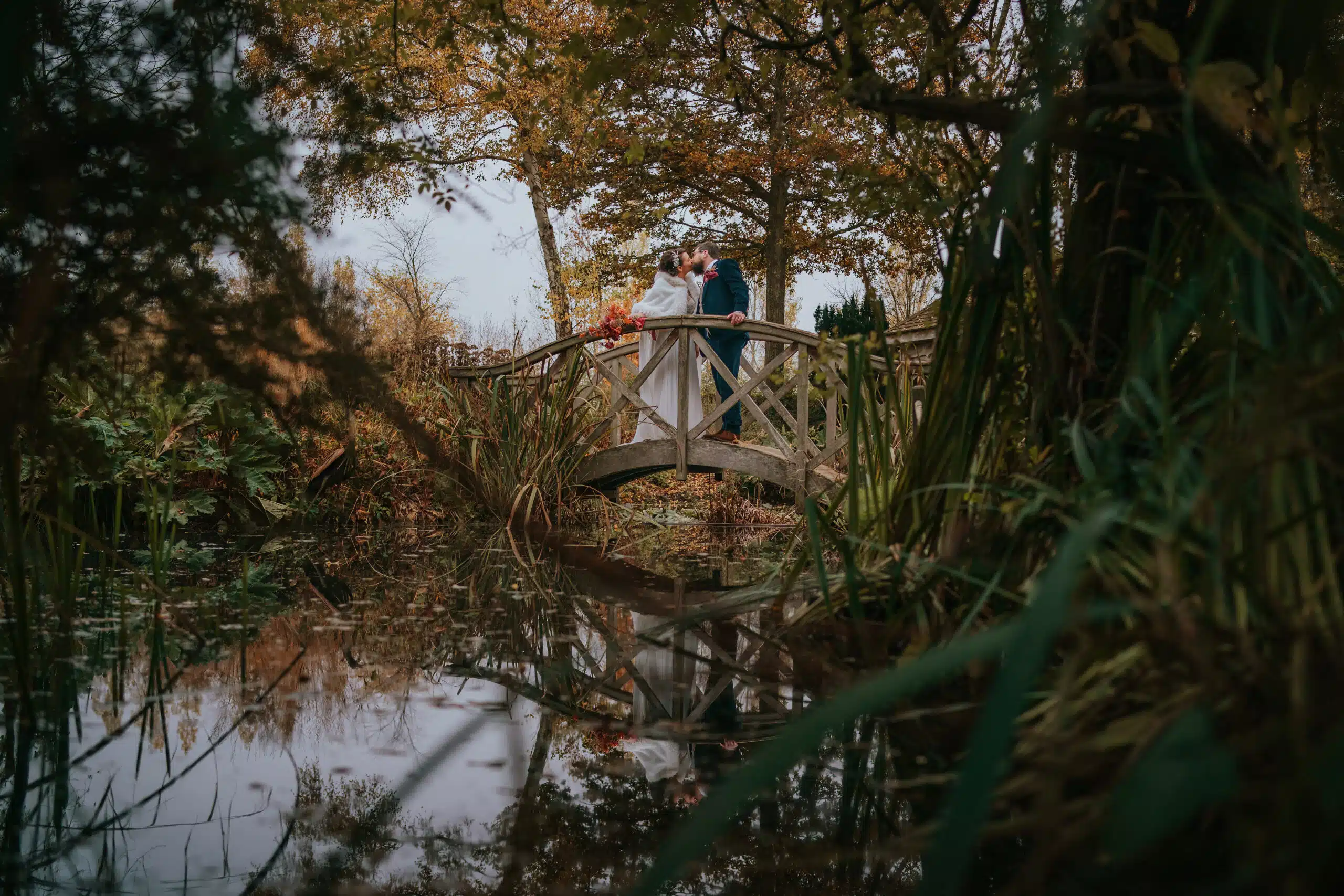 Bride and Groom at outdoor garden wedding venue having a kiss on the Monet Bridge