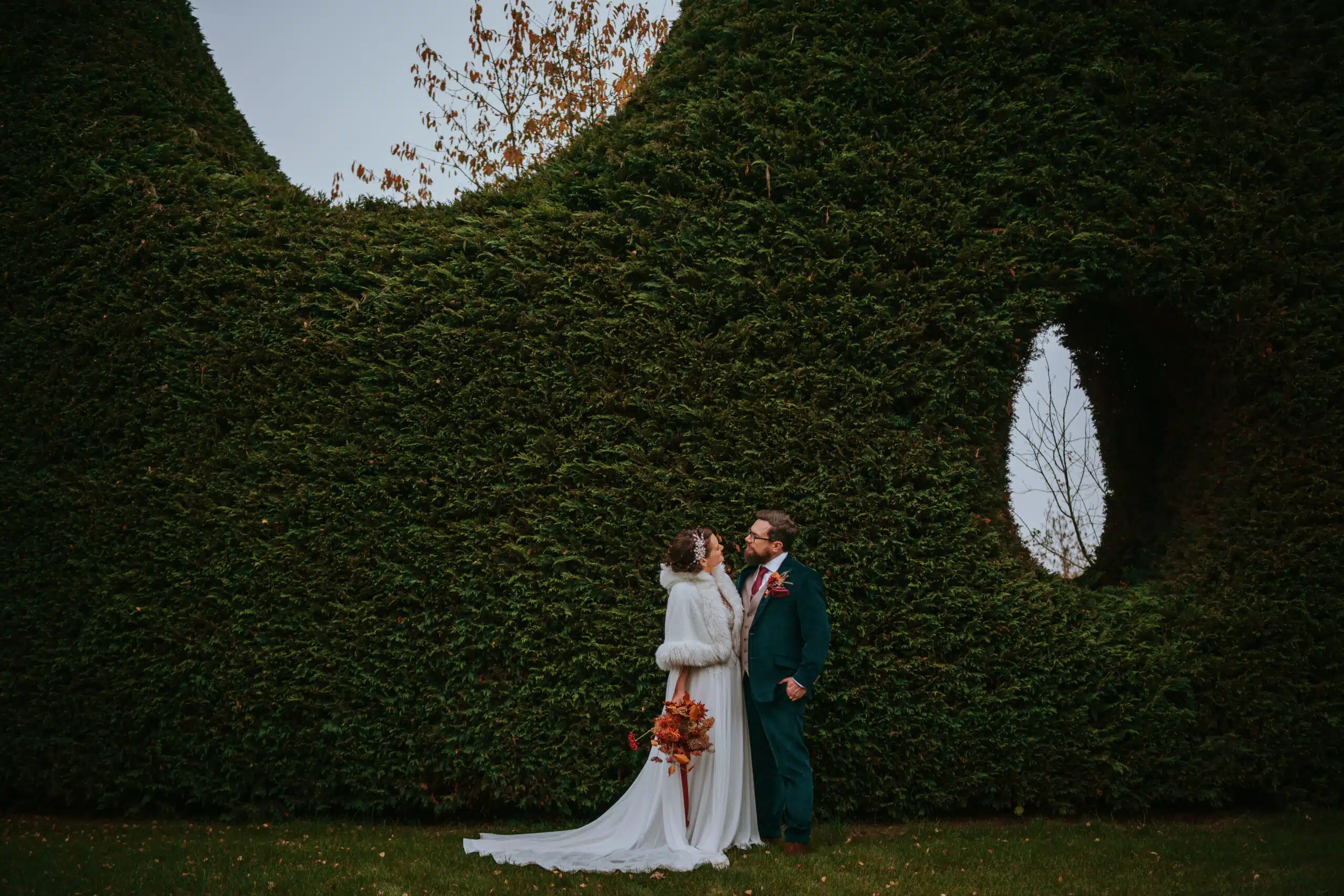 Bride and Groom having couple photos in front of evergreen hedges at garden wedding venue based in Hertfordshire