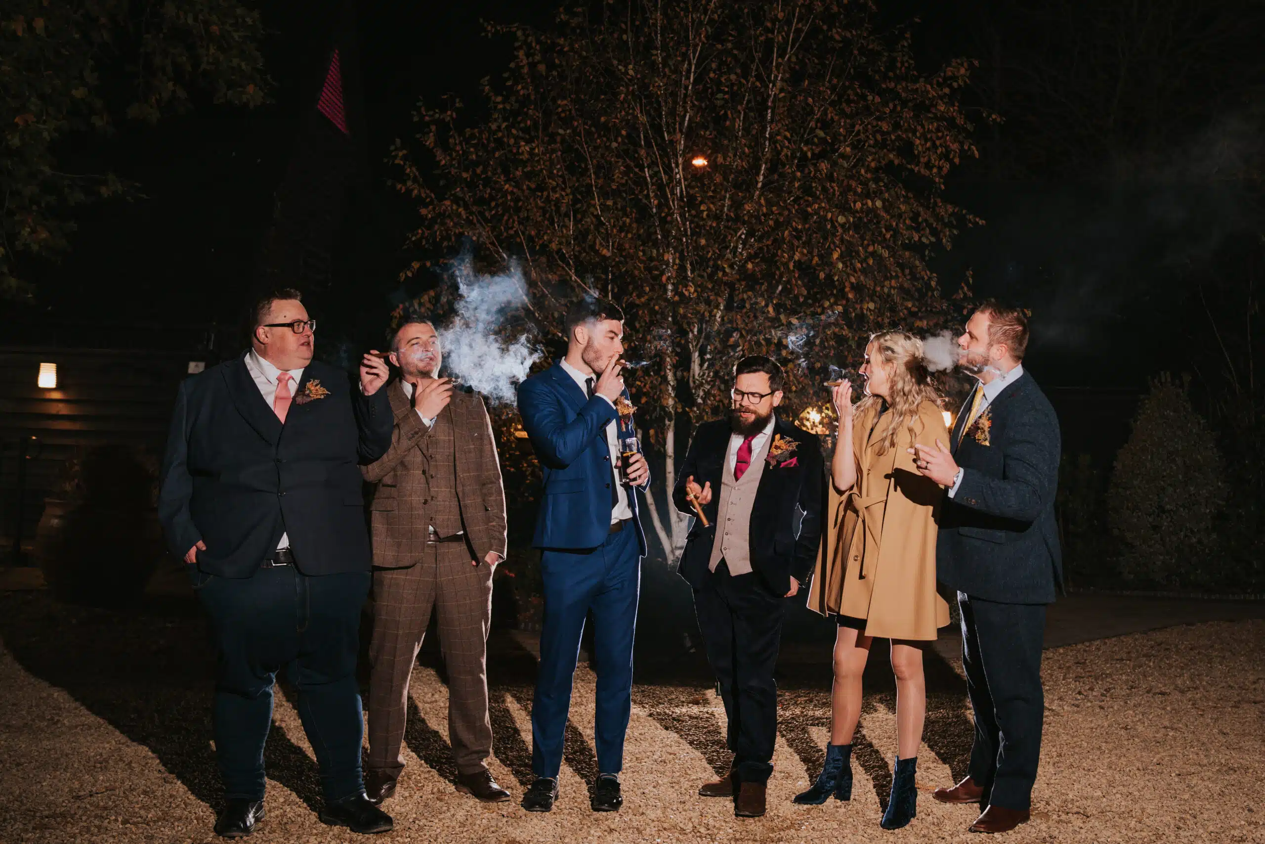 Groom and his guests enjoying a cigar in the evening at barn wedding venue
