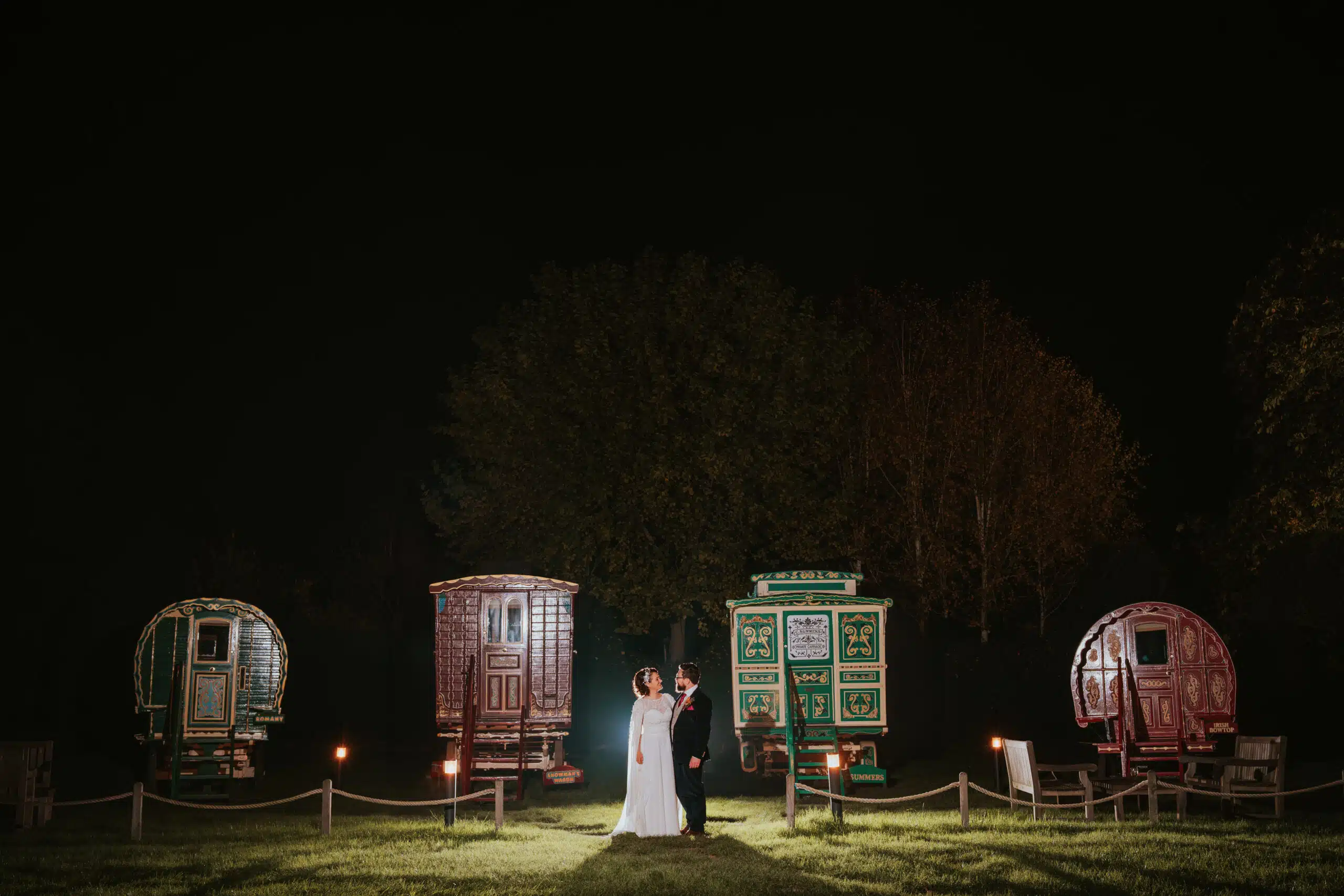 Bride and Groom at twilight in front of the romany caravans at South Farm wedding venue