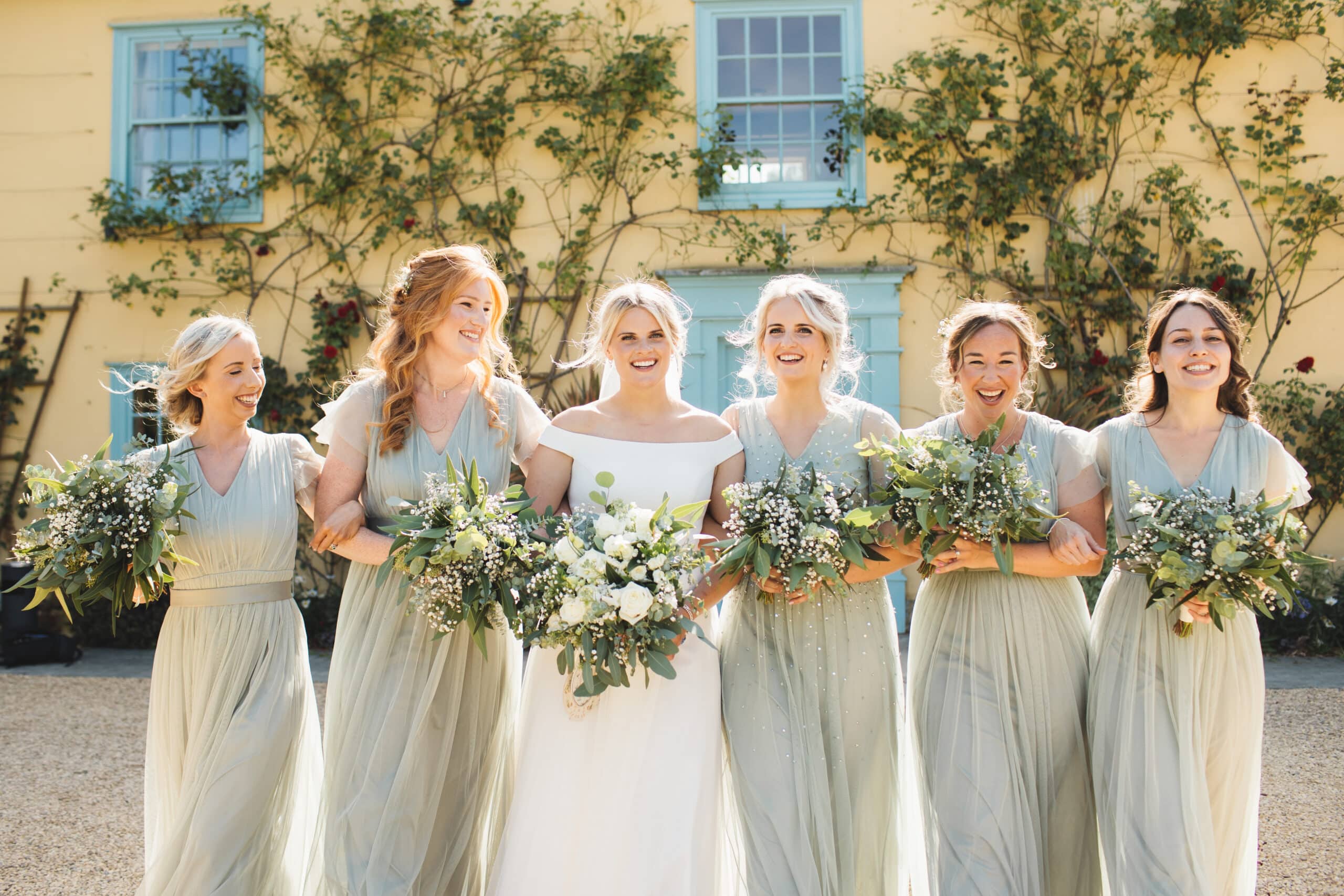 Bride and bridesmaids on wedding day in front of countryhouse wedding venue