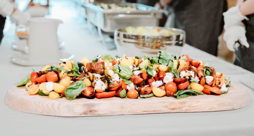 Delicious home-grown Heritage tomato salad served on a wooden board on buffet table 