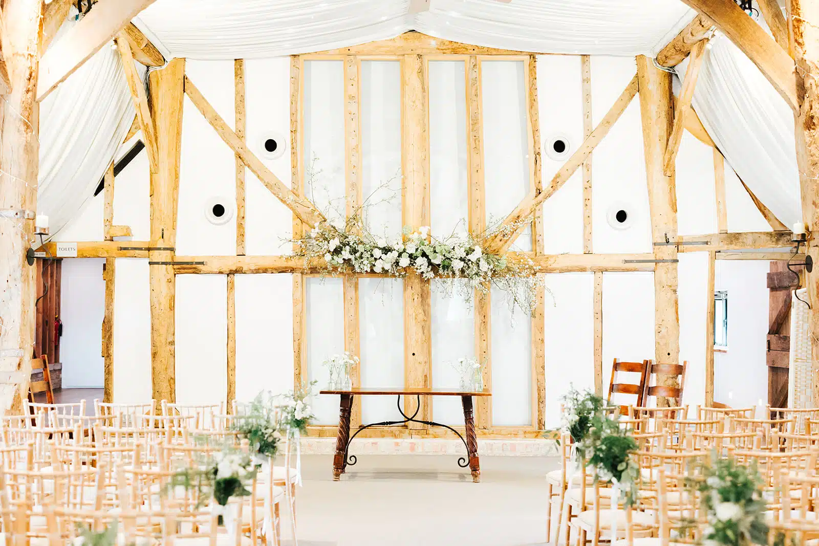 Ceremony set up with white florals in the rustic Tudor Barn wedding venue based in Cambridgshire