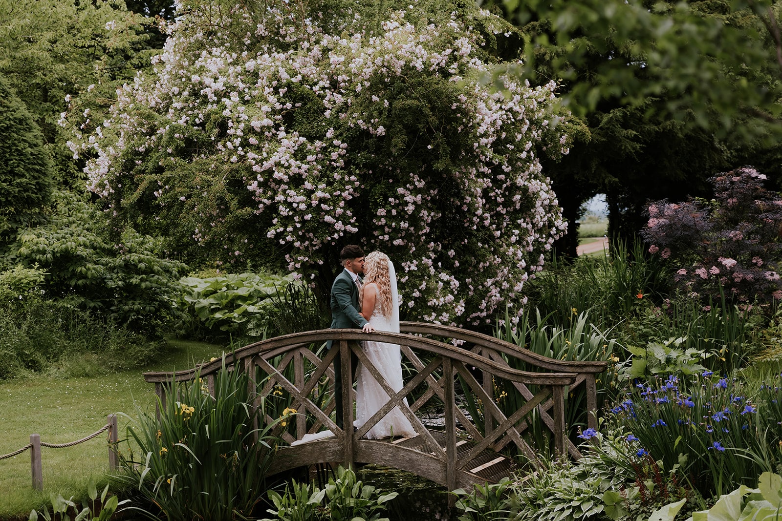 Bride and Groom standing on the Monet Bridge at outdoor country wedding venue with eco conscious values