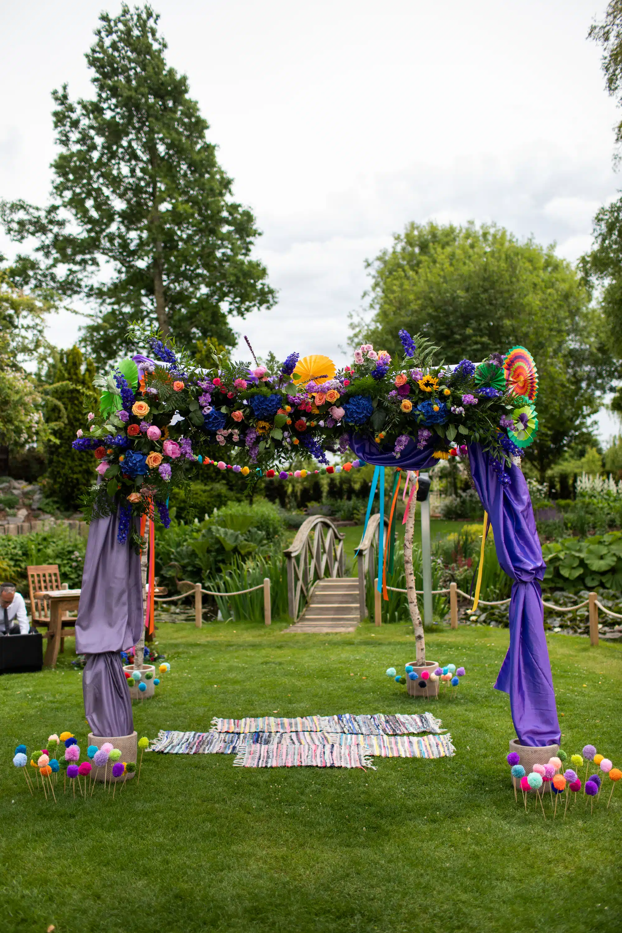 Outdoor ceremony arch with bold vibrant colours in the formal gardens at South Farm wedding venue
