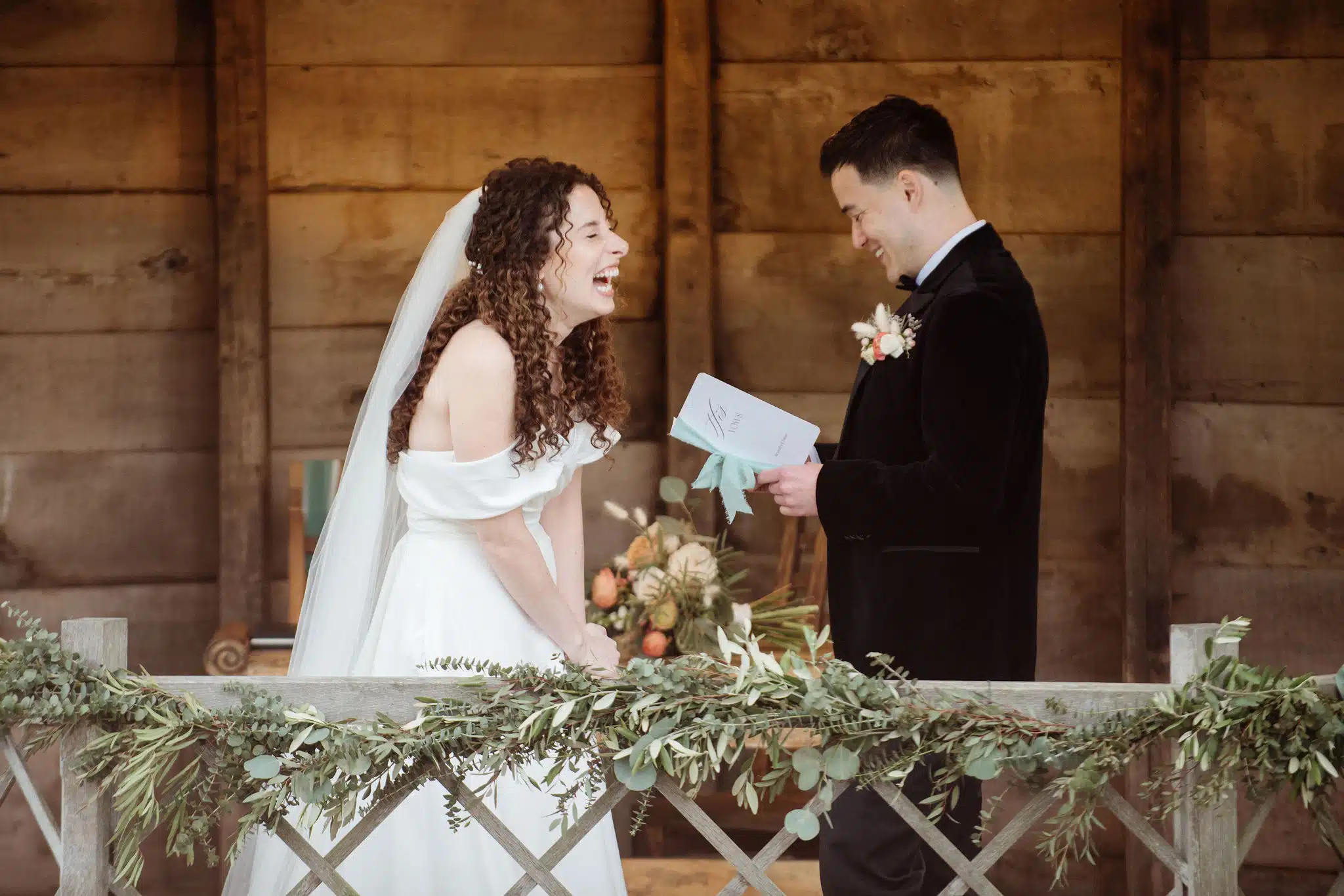 Bride and Groom standing in the Summerhouse, Bride smiling as the groom reads his personal vows to her