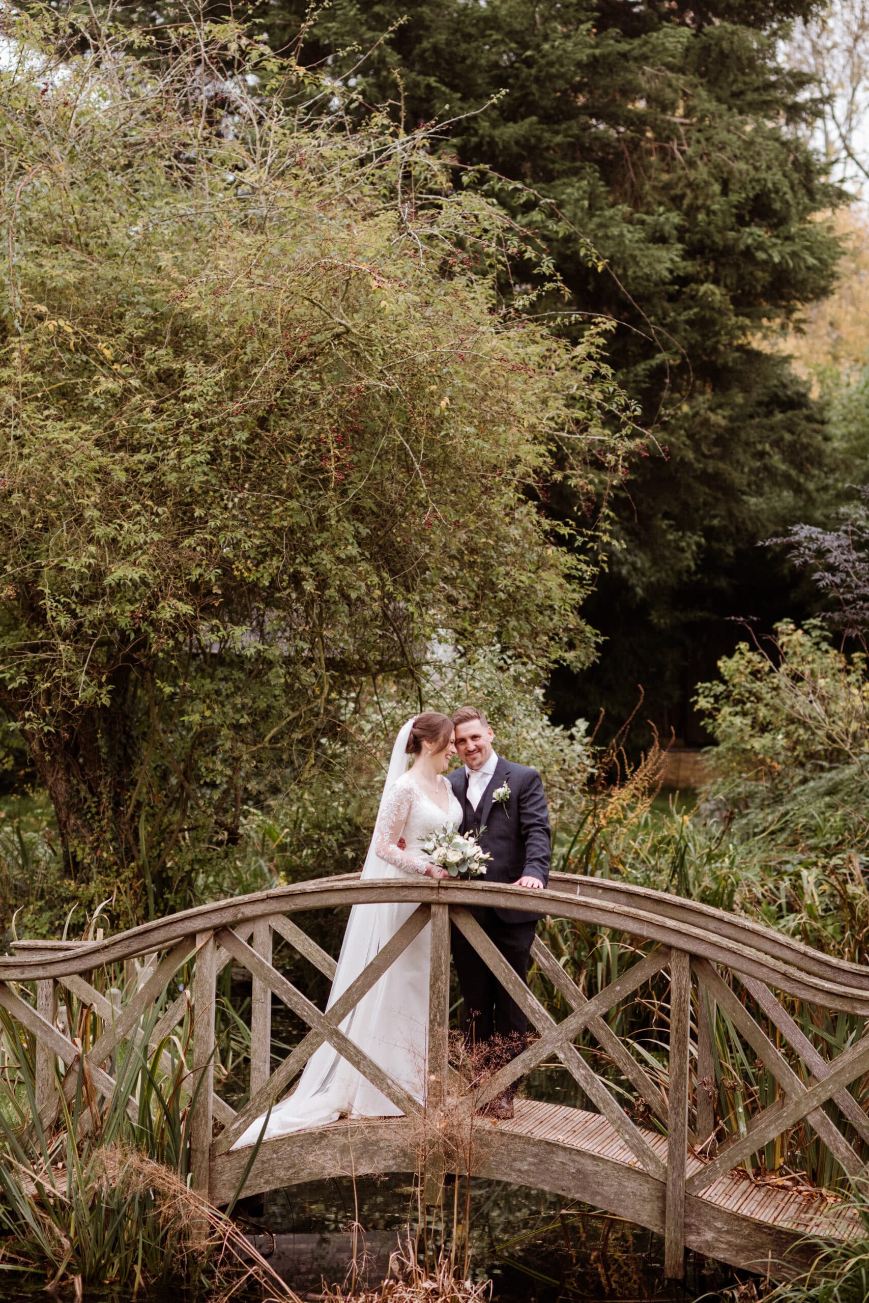 Bride and Groom standing on the Monet Bridge in the formal gardens at outdoor garden wedding venue