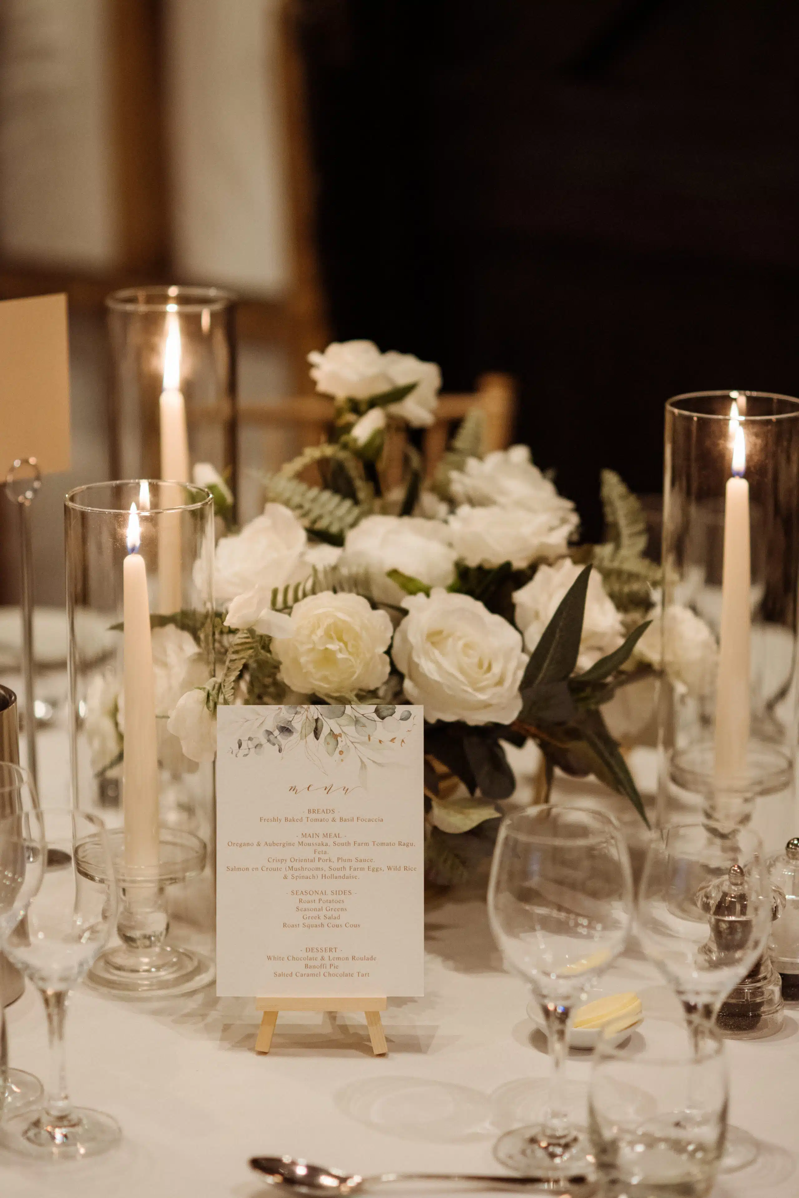 Elegant styling in the Tudor Barn with soft candle light and white florals on guests tables in the Tudor Barn