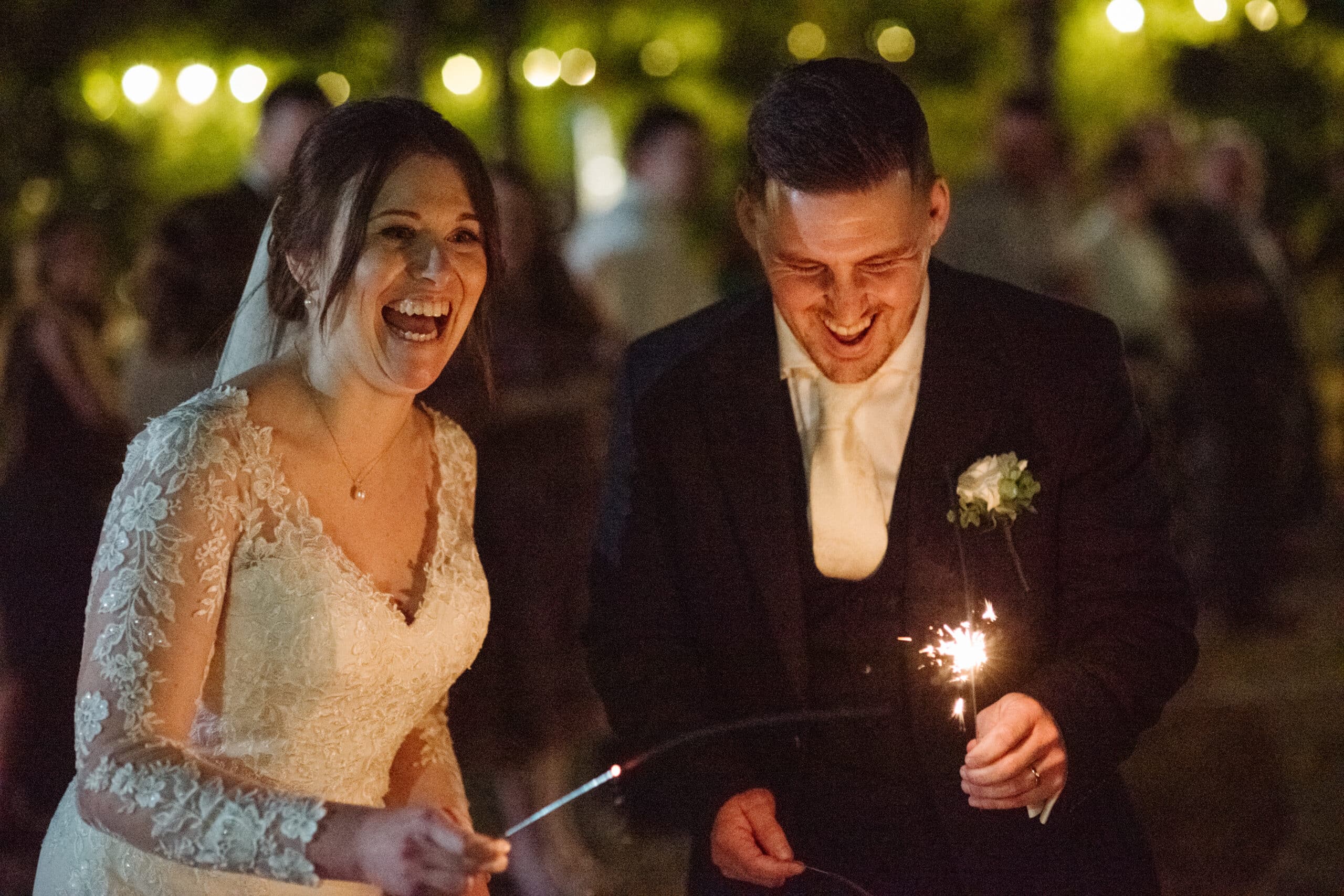Bride and groom enjoying a sparkler photo in the courtyard at barn style wedding venue