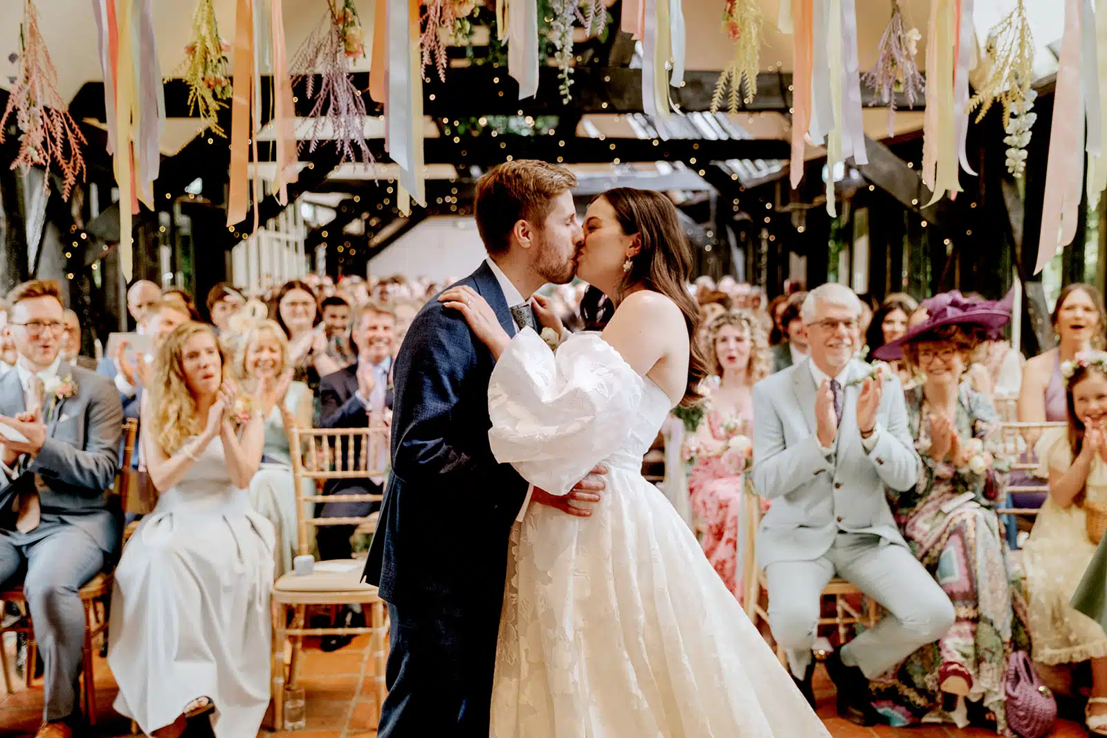 Bride and Groom sharing a kiss after the 'I Do's' in the Old Dairy at eco friendly wedding venue in Cambridgeshire