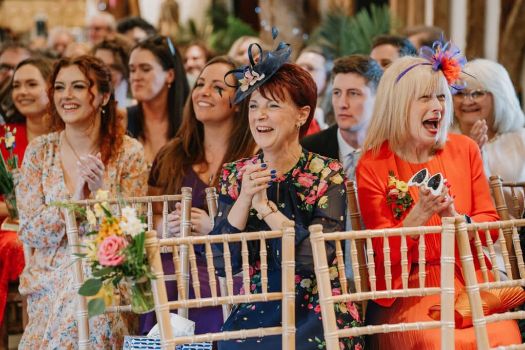 Happy guests cheering on the happy couple during their ceremony in the rustic Tudor Barn at outdoor wedding venue