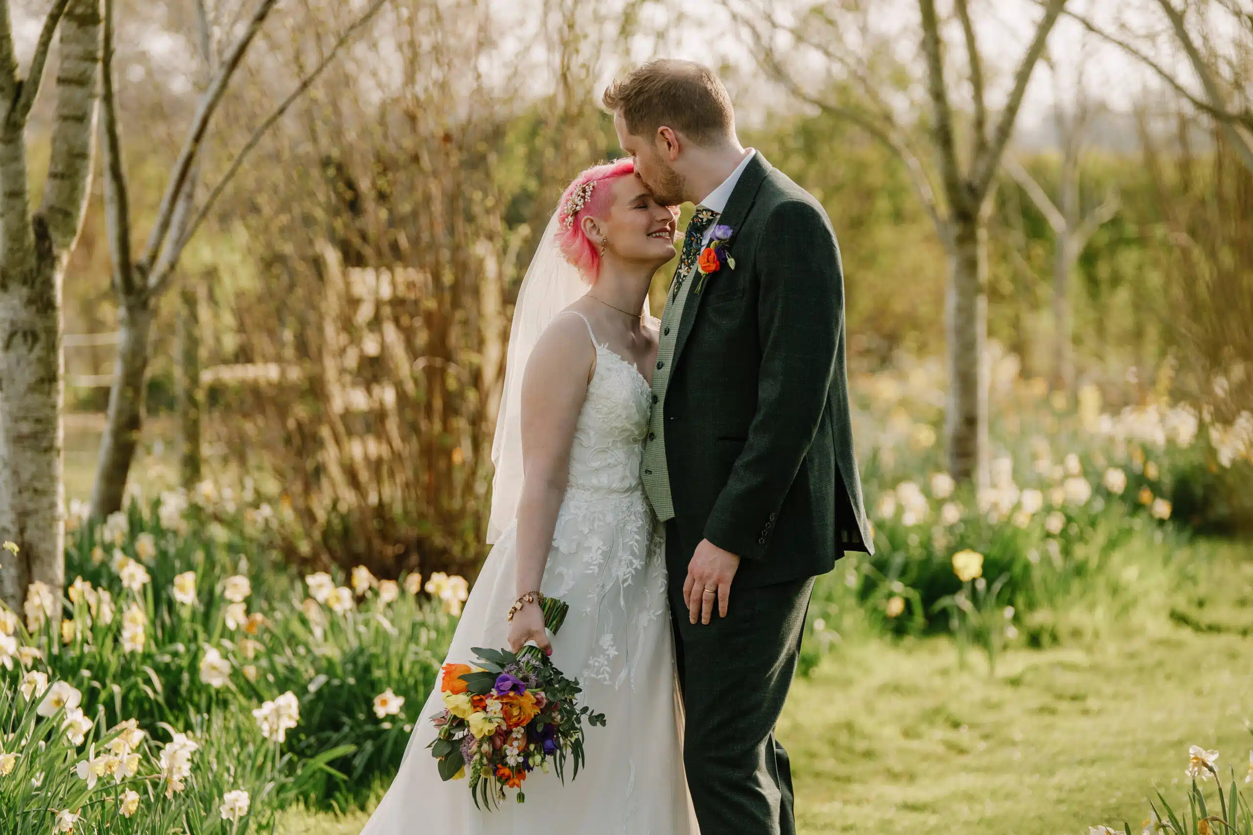 Bride and Groom standing in amongst the yellow daffodils at countryside wedding venue in Bedfordshire
