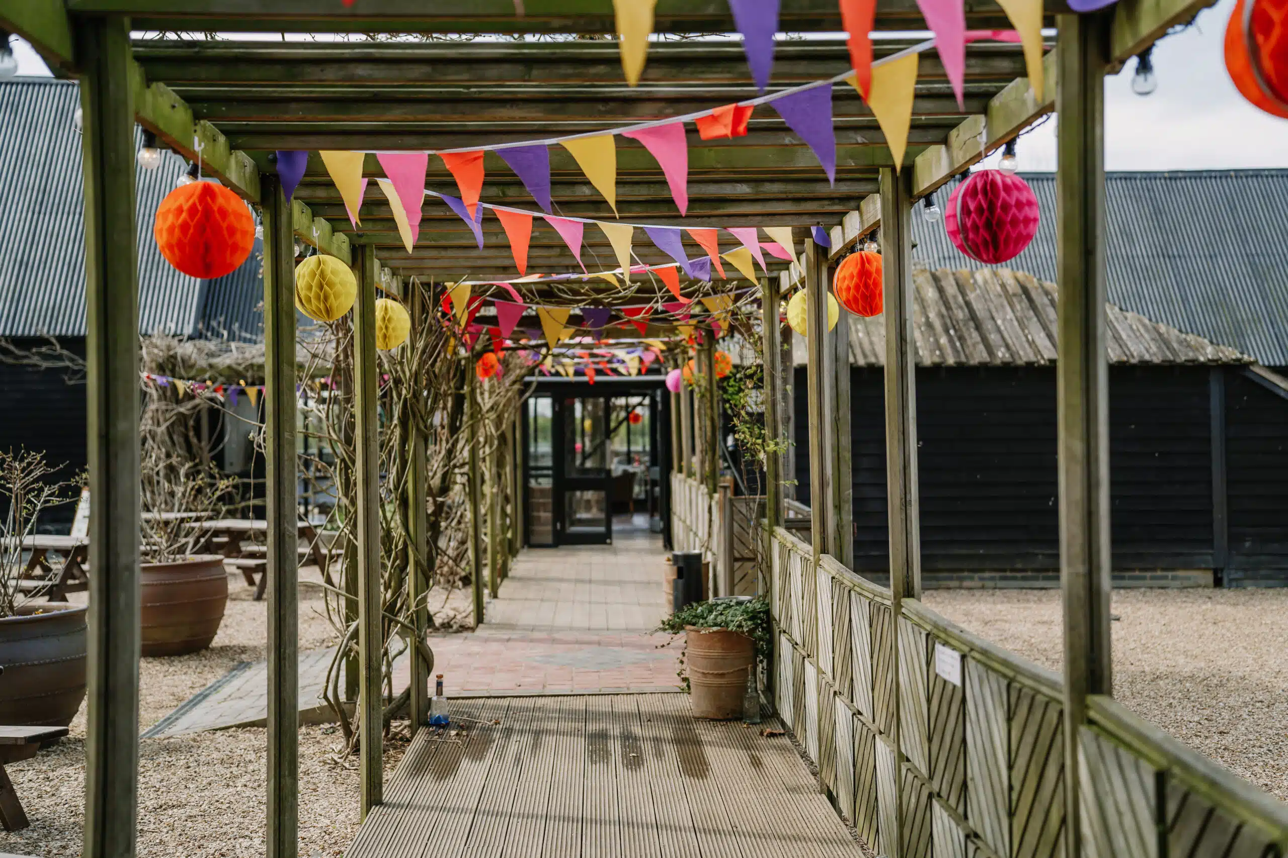 The walkway leading to the Tudor Barn overflowing with bright colourful wedding bunting 