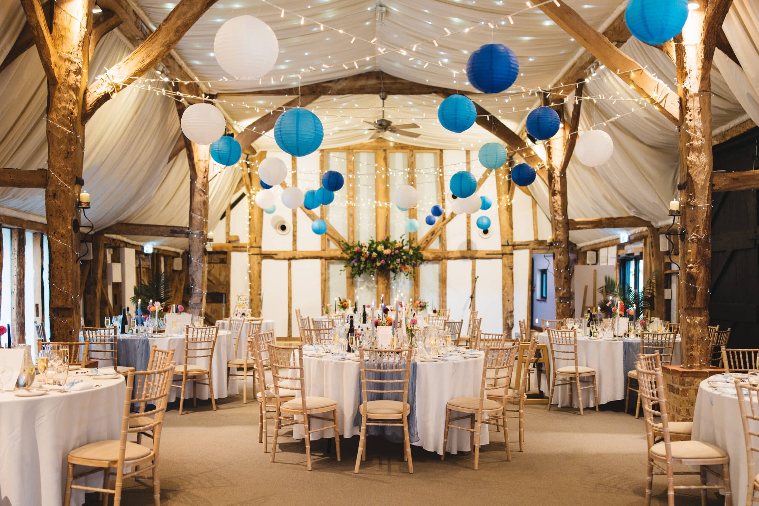 South Farm stunning barn set up for dining with round tables and blue and white paper ceiling lanterns