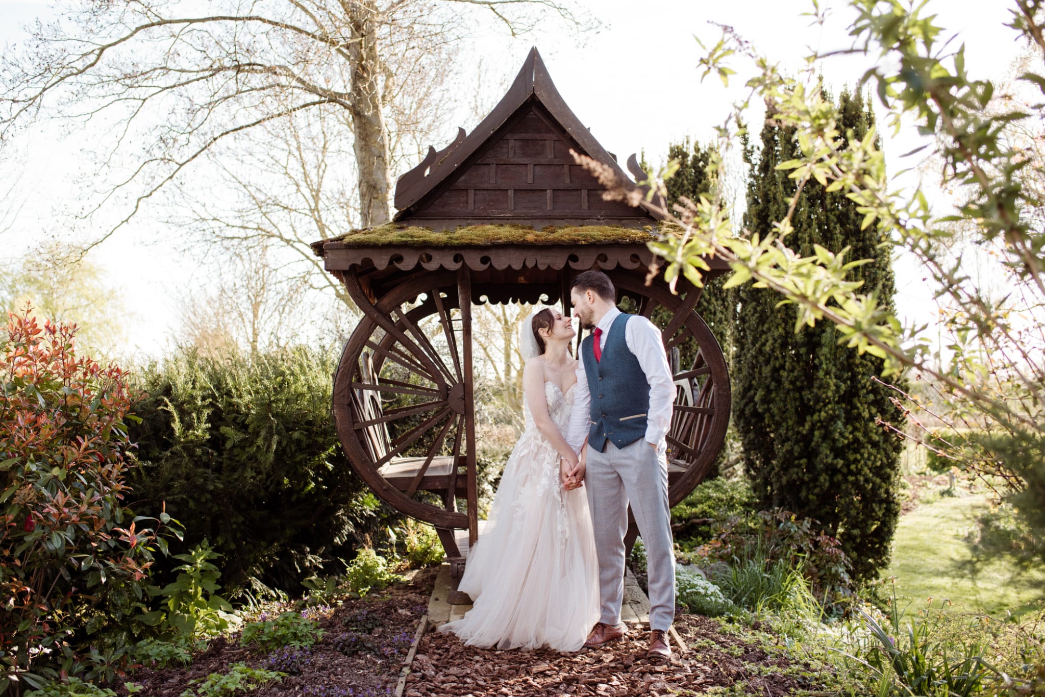 Bride and Groom standing in front of Thai pergoda at outdoor garden wedding venue in Hertfordshire