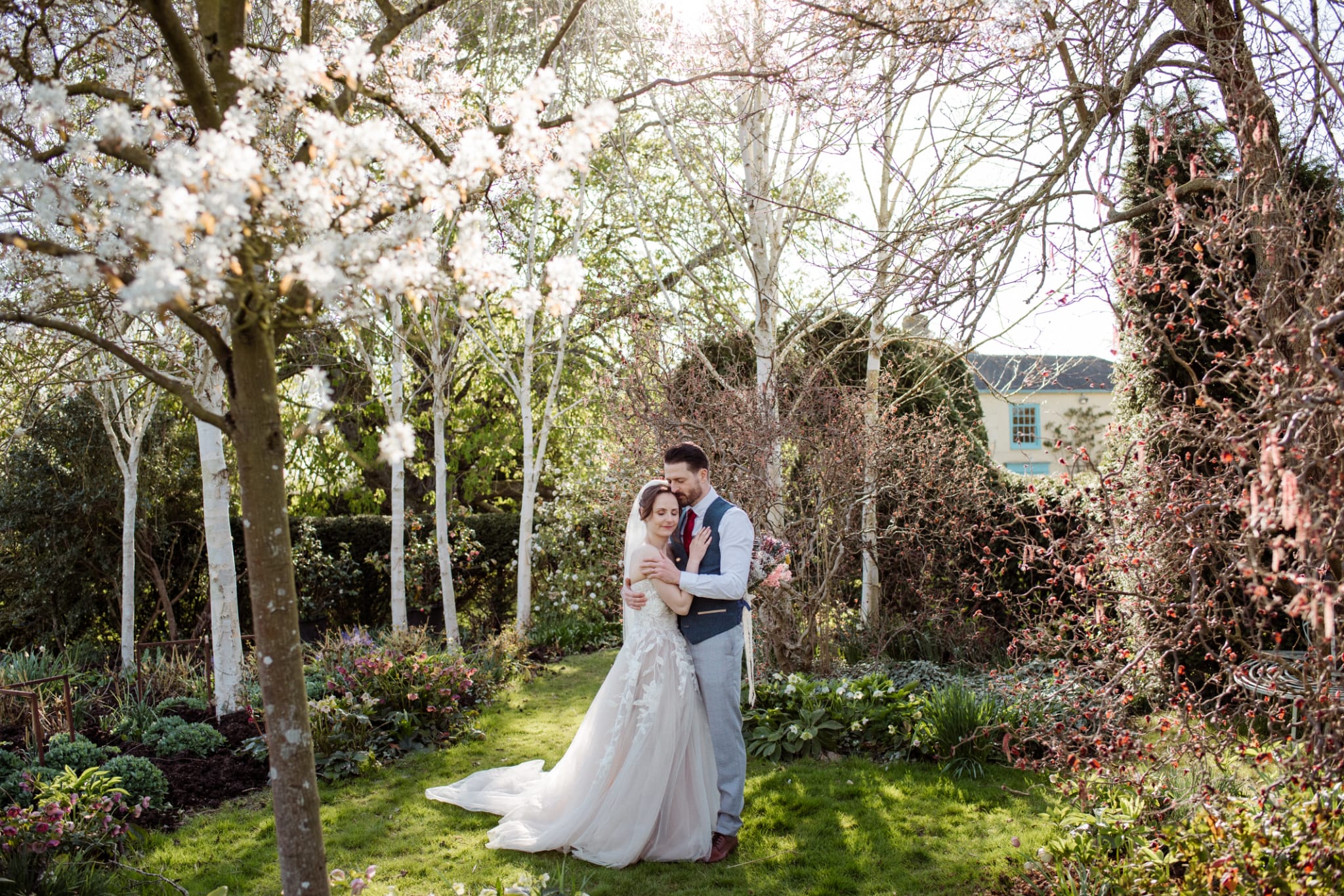 Couple standing having a special moment with spring blossoms overhead at stunning outdoor garden wedding venue in Hertfordshire