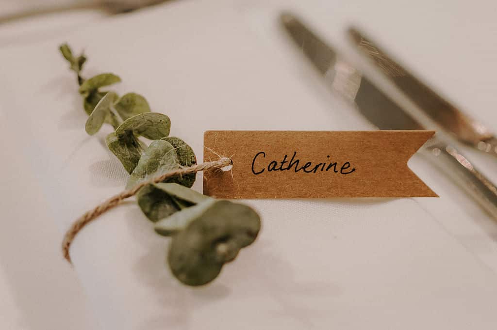 Pretty plant clipping used as place name setting with name on sustainable brown paper