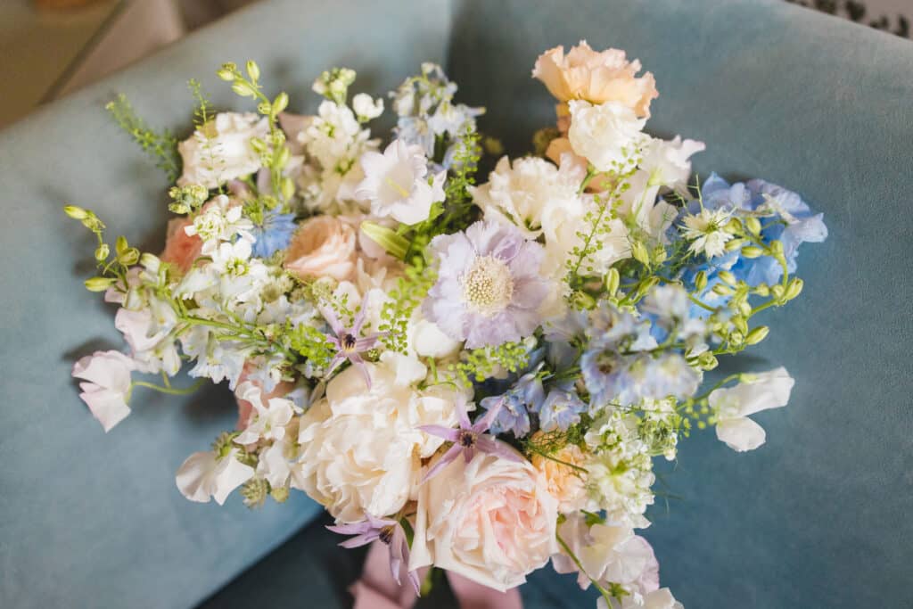 Beautiful pastel pink, blue and cream wildflowers wedding bouquet with a blush pink bow