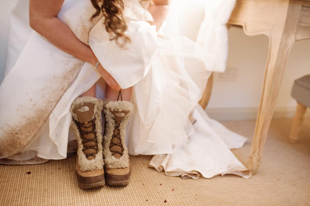 Bride putting on her snow boots in the Bridal Suite at South Farm winter wedding venue