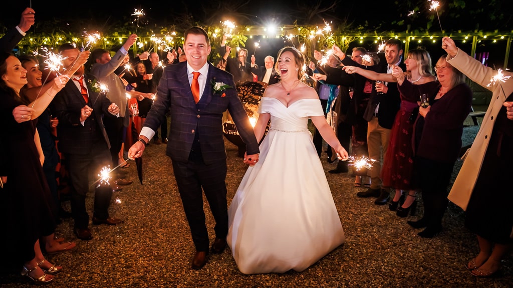 Bride and Groom walking down 'sparkler shot' in the courtyard at barn wedding venue in Hertfordshire