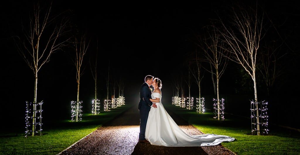 Bride and Groom sharing a kiss on the fairy-lit driveway at South Farm intimate winter wedding venue in Hertfordshire