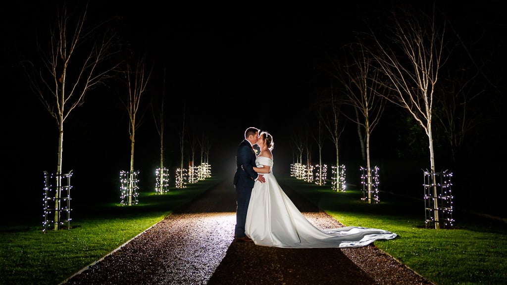 Bride and Groom sharing a kiss on the fairy-lit driveway at South Farm in the winter