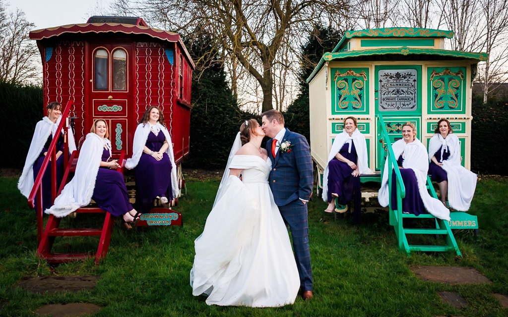 Bride, groom and their bridal party standing in front of the Romany Caravans at South Farm wedding venue in Hertfordshire