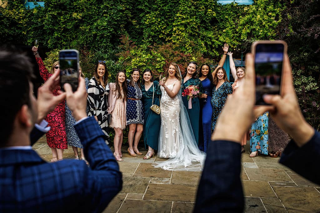 Cameras out and cheese! Bride with her wedding guests on the Garden Terrace at barn wedding venue in Cambridshire