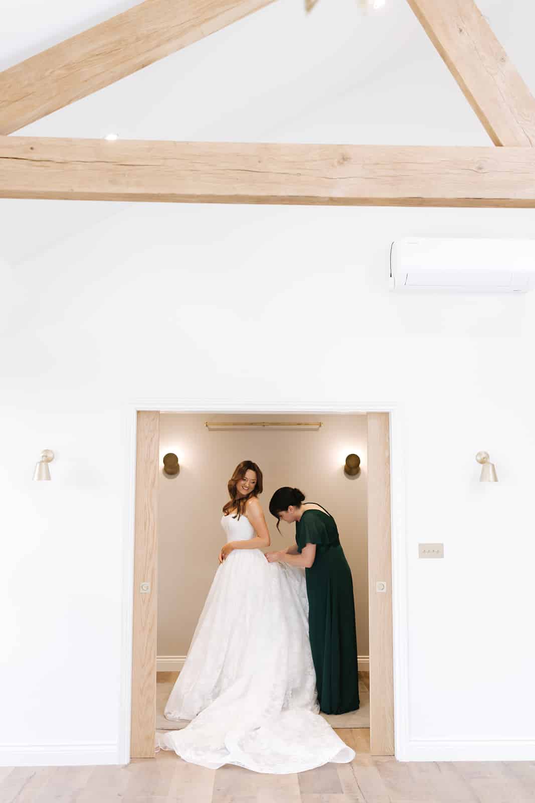 Bride getting ready in the 'private dressing' room with white walls and elm oak beams