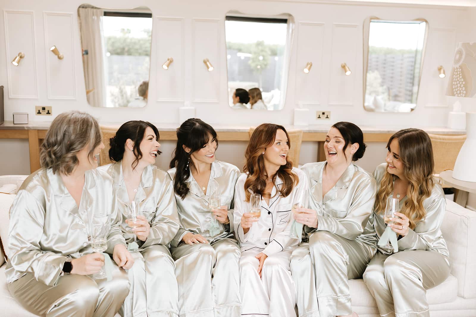 Bride and her bridal party having a celebratory drink with beautiful make up station behind them