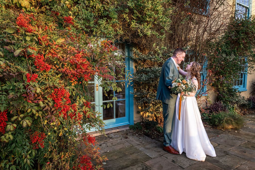 Couple embracing near colorful foliage.