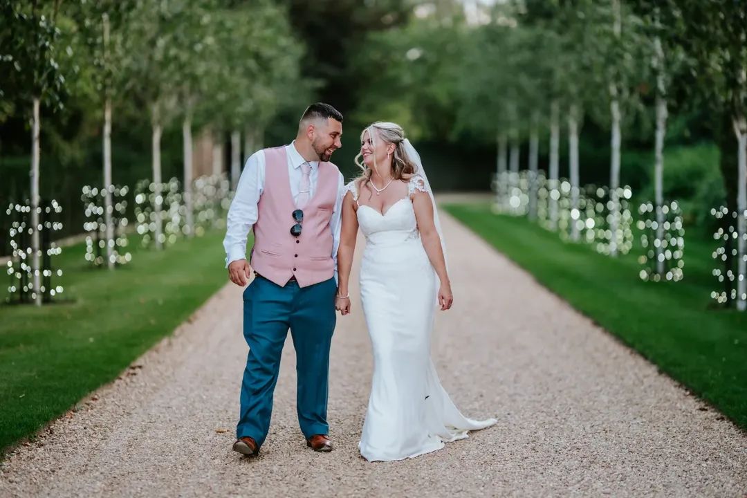 Bride and groom share a moment on sweeping driveway with twinkling fairy lights at countryside wedding venue