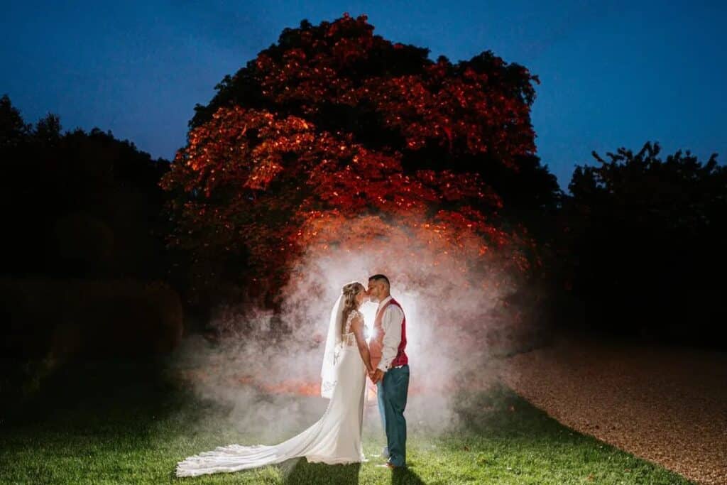 Bride and groom in gardens lit up at night