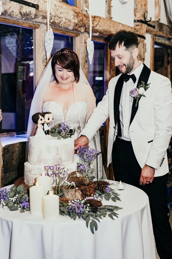 Bride and groom cut their wedding cake at rustic barn wedding venue