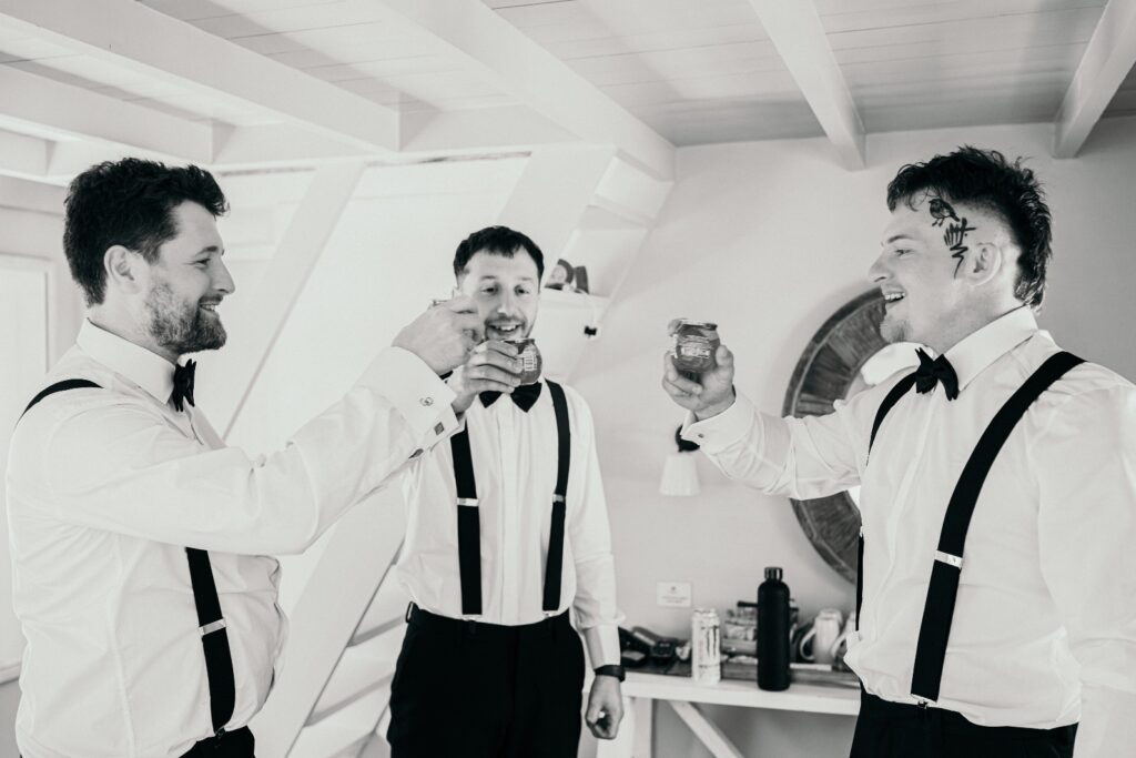 Black and white photo of groom and groomsmen on wedding day raising a toast