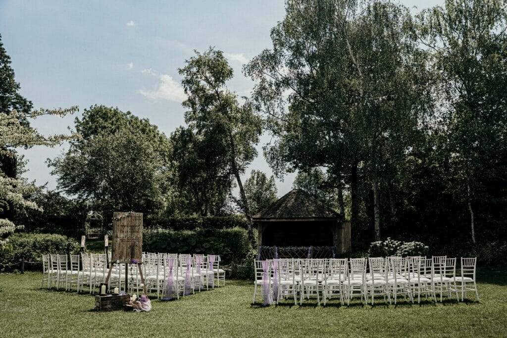 Beautiful garden summer house set for ceremony with white chairs and pretty rustic styling