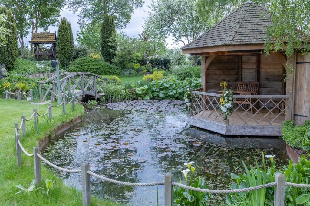 Pretty garden summerhouse next to pond at countryside wedding venue