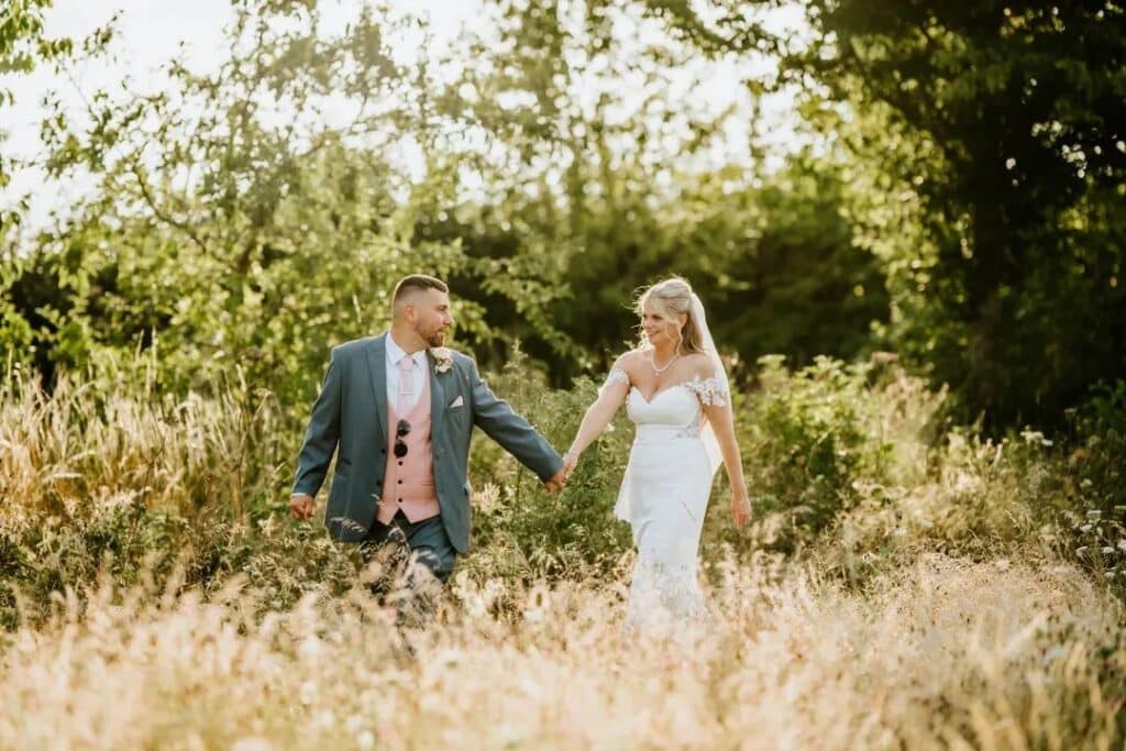 Bride and groom walk through rustic gardens at countryside wedding venue